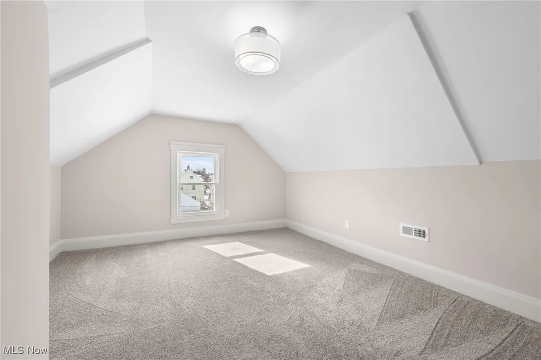 Bedroom with lofted ceiling, baseboards, and carpet