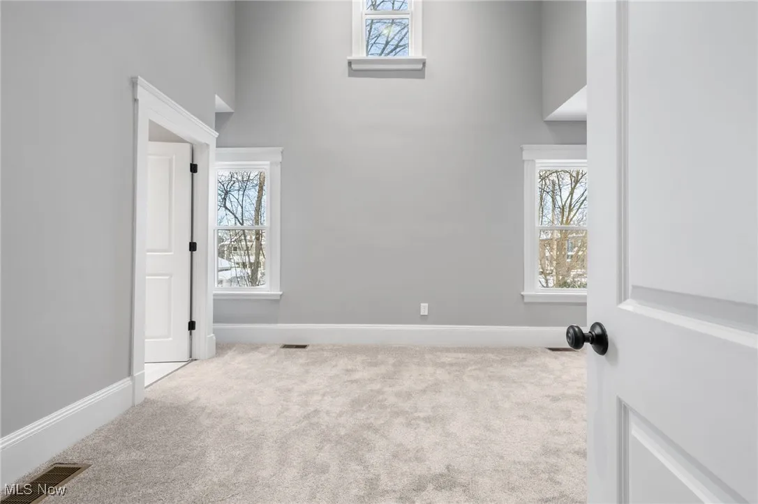Owner's suite featuring a towering ceiling, carpet floors, and a healthy amount of sunlight