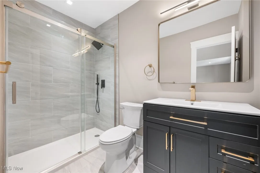 Primary bath with a shower stall, toilet, vanity, and baseboards
