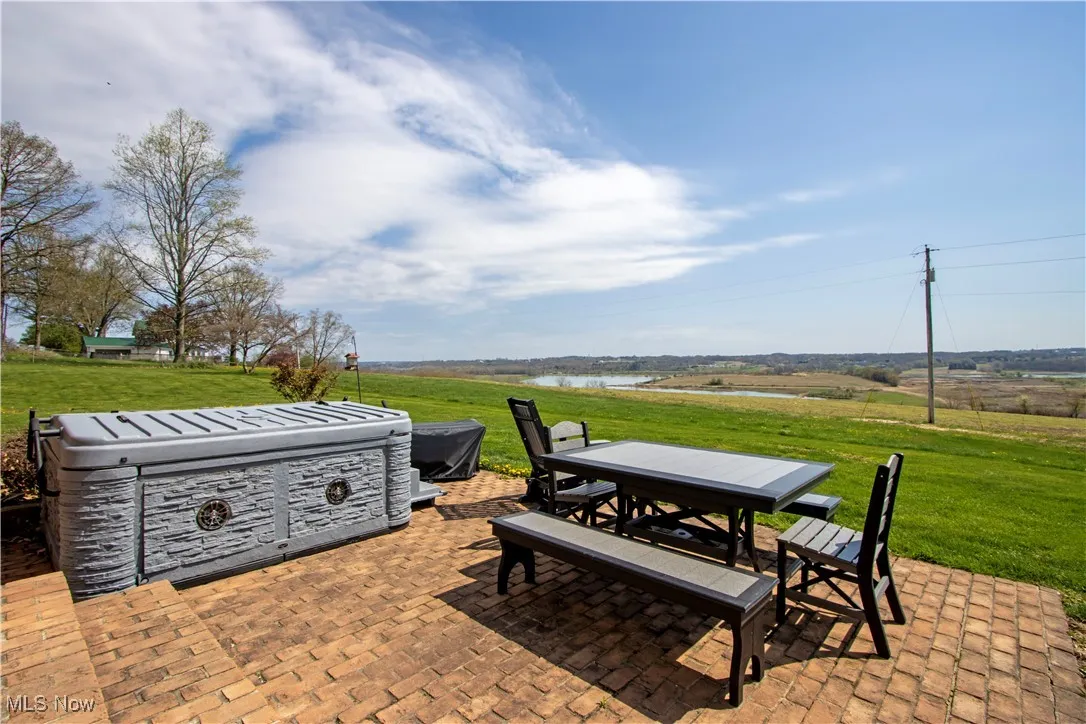 View of patio featuring outdoor dining area, a hot tub, and a water view