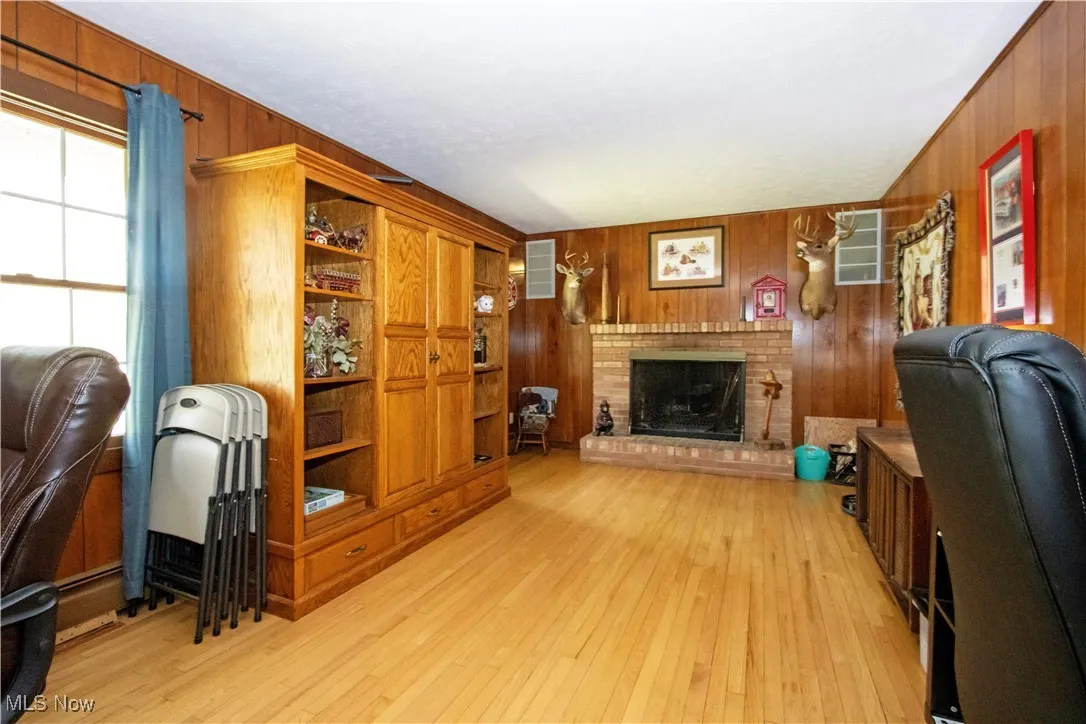 Office area with light wood-style flooring, wood walls, and a fireplace