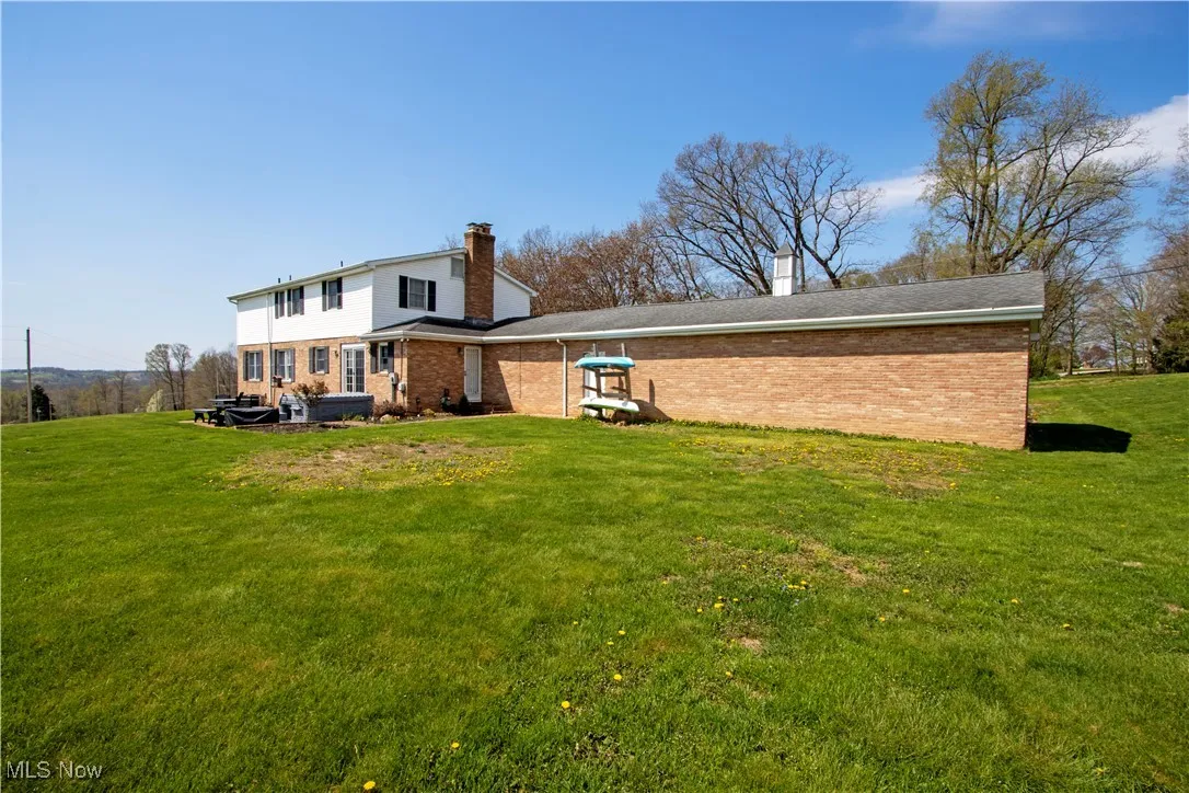 Back of property with a chimney, brick siding, and a yard
