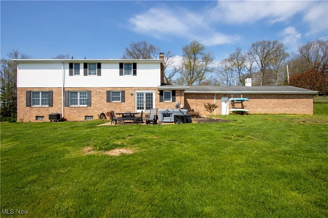 Back of property featuring a lawn, a chimney, central air condition unit, and brick siding
