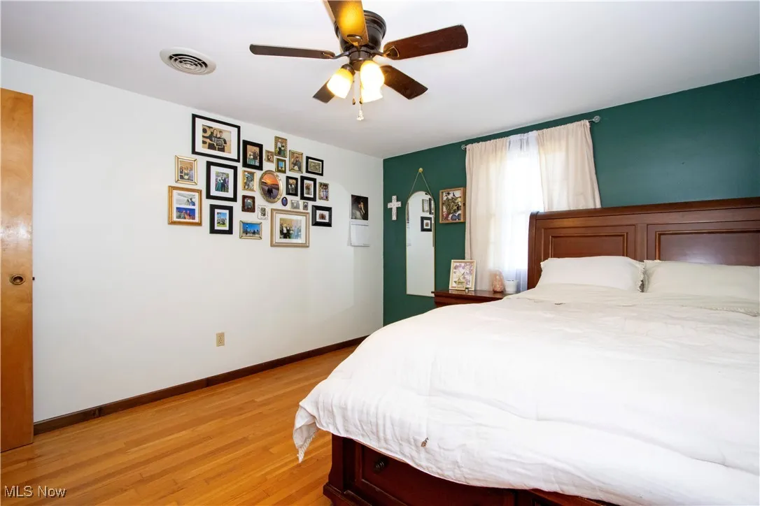 Bedroom with ceiling fan, visible vents, light wood-type flooring, and baseboards