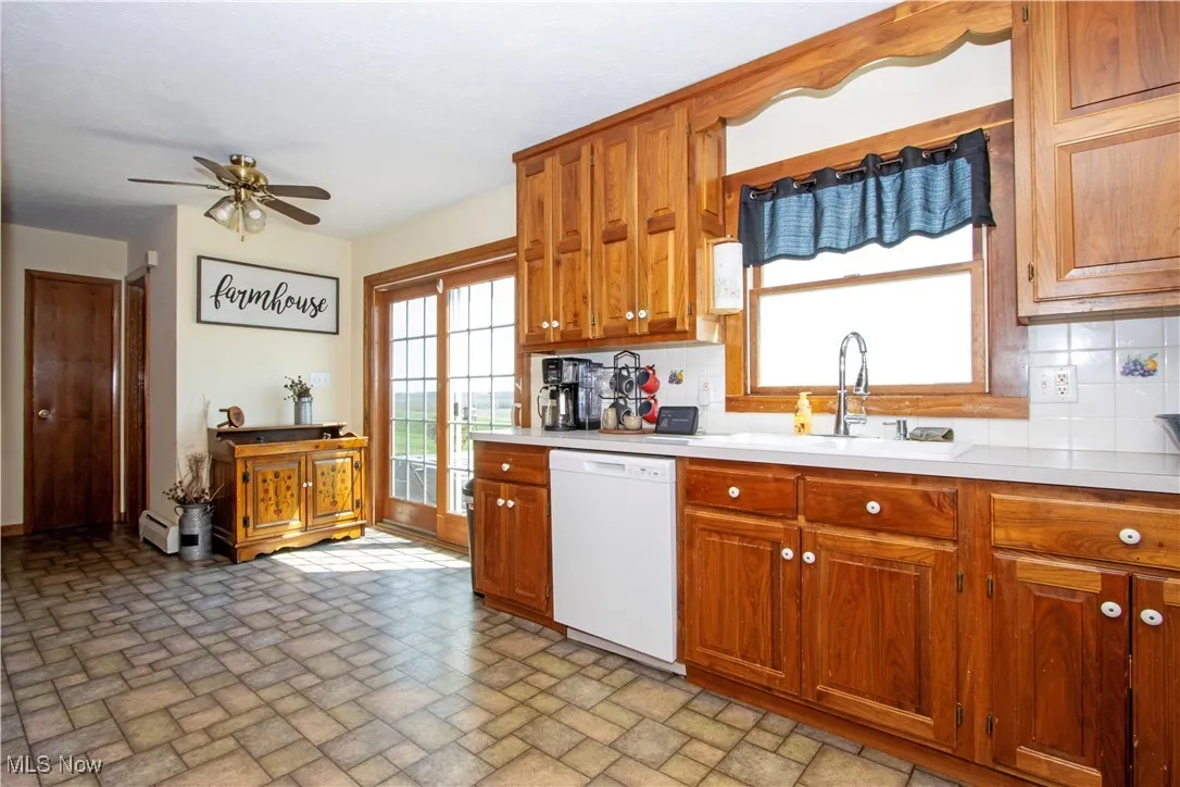 Kitchen with a sink, a ceiling fan, backsplash, light countertops, and dishwasher