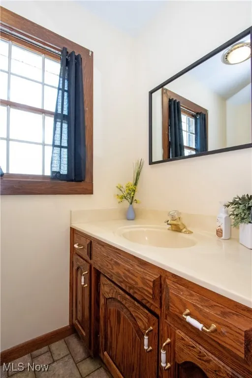 Bathroom with baseboards, stone finish floor, and vanity
