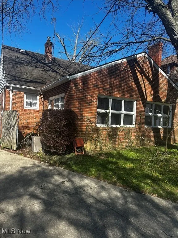 View of side of property with a chimney and brick siding
