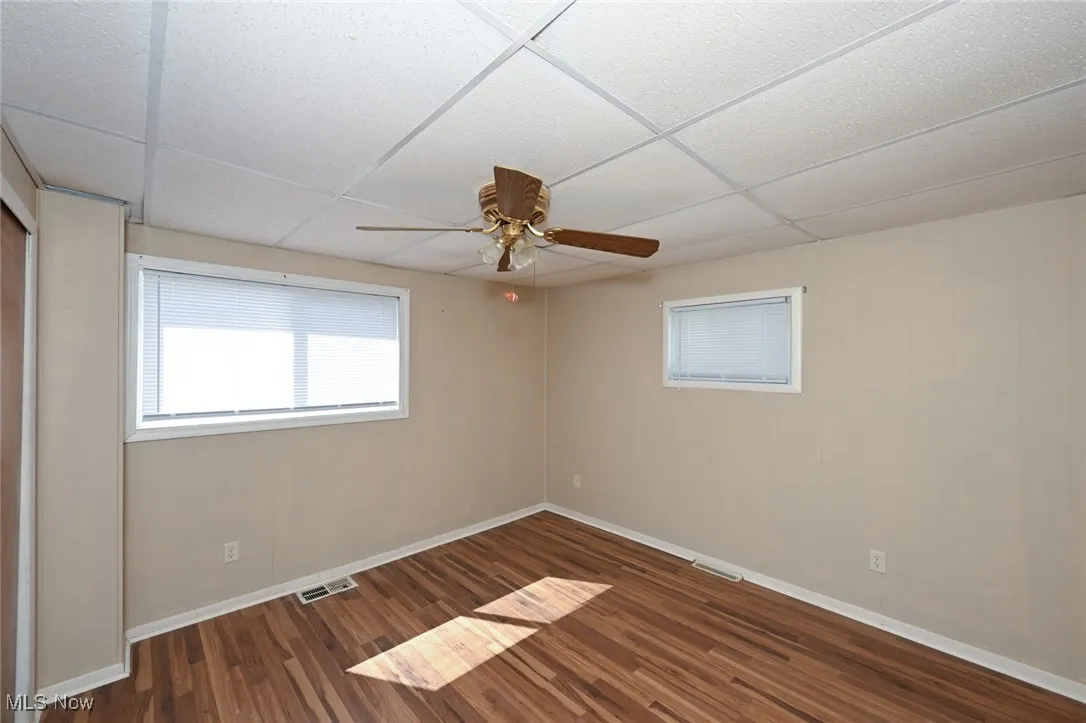 Spare room featuring visible vents, wood finished floors, a ceiling fan, and a paneled ceiling