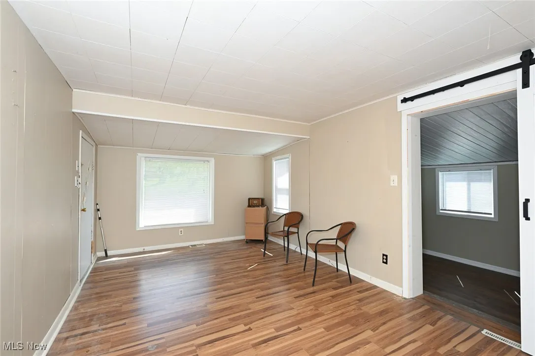 Unfurnished room with baseboards, a barn door, visible vents, and light wood-style floors