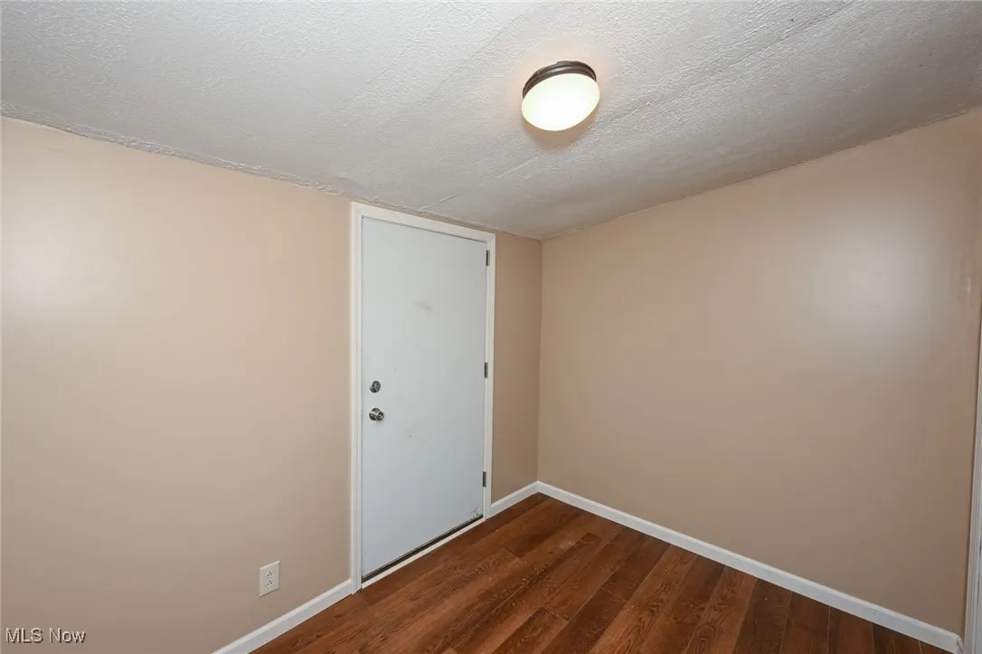 Spare room featuring dark wood-type flooring, a textured ceiling, and baseboards