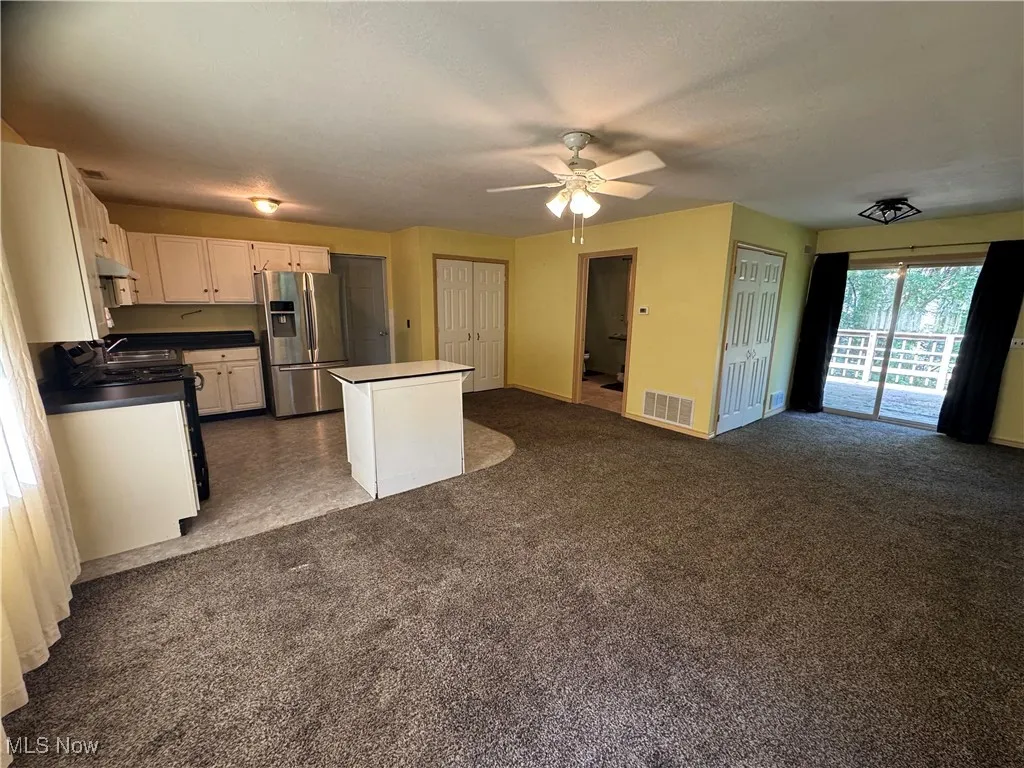 Kitchen featuring stainless steel fridge, a kitchen island, range, and open floor plan