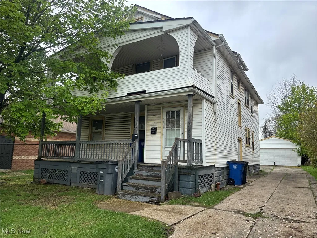 View of front of house with an outbuilding, a garage, covered porch, and a balcony