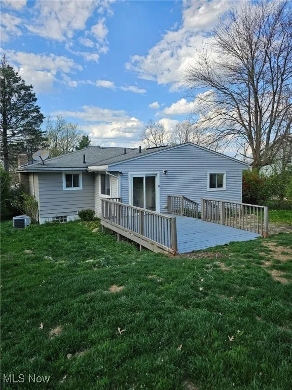 Rear view of property featuring a deck, central AC, and a yard