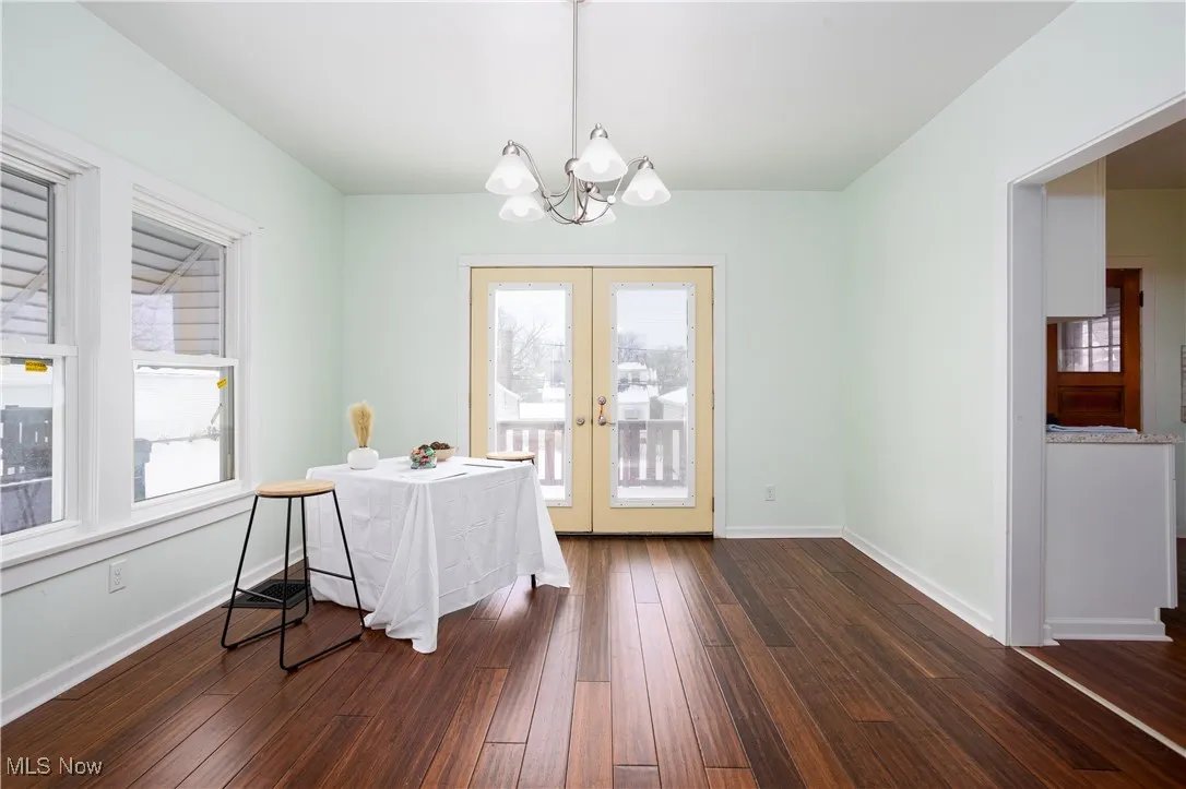 Dining room featuring dark wood-style floors, a chandelier, french doors, and a healthy amount of sunlight