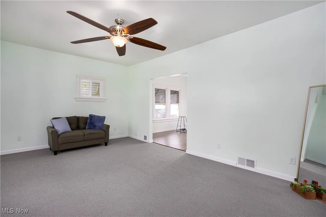 Sitting room with carpet flooring, visible vents, ceiling fan, and baseboards