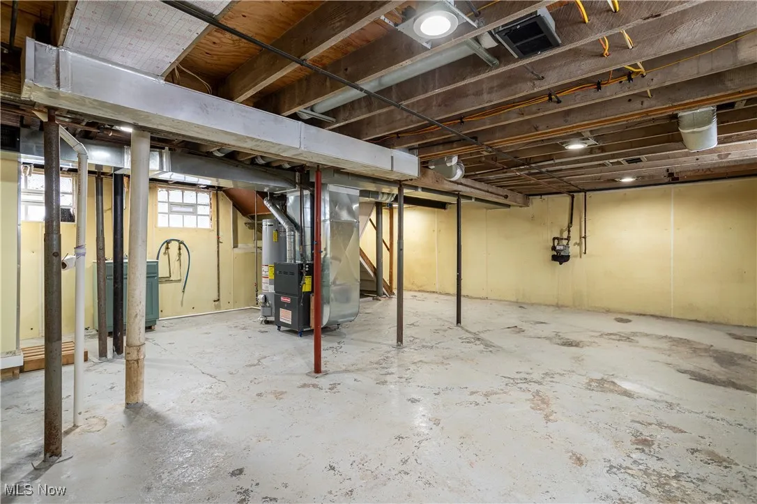 Basement featuring visible vents, heating unit, and water heater