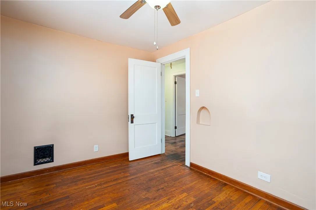 Unfurnished room with baseboards, a ceiling fan, and dark wood-style flooring