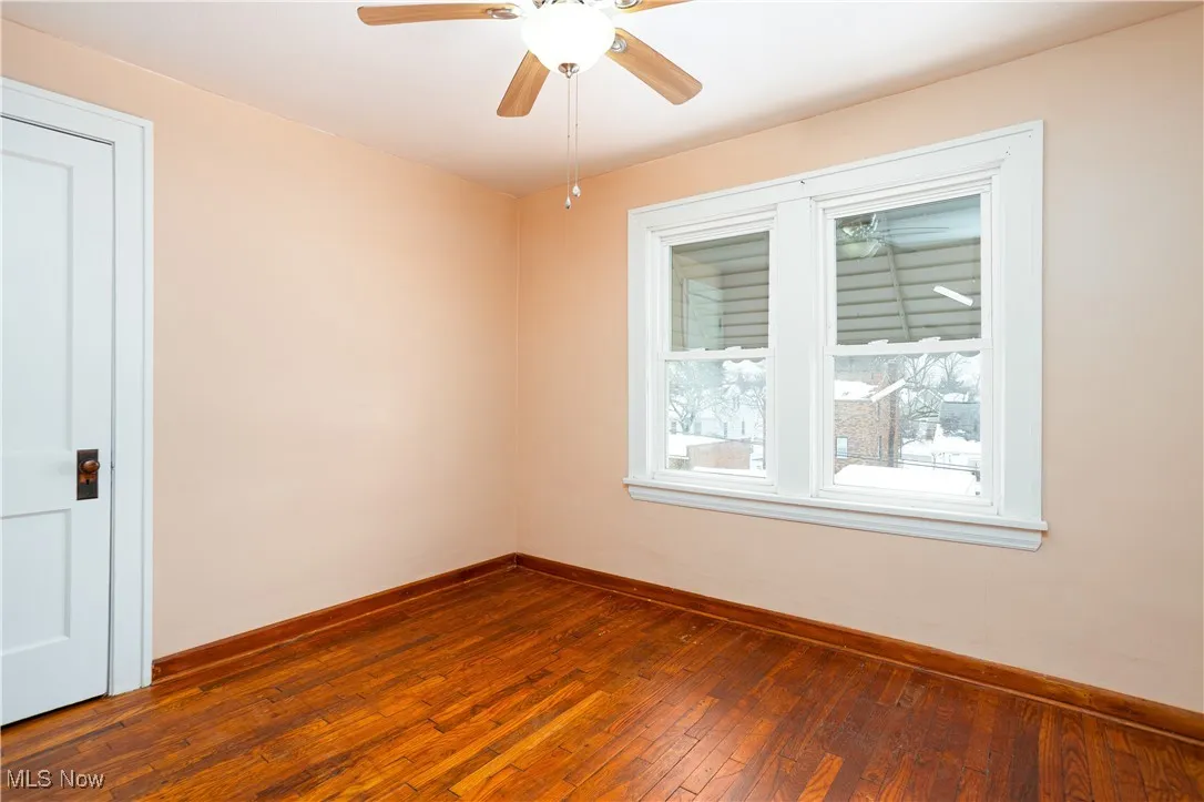 Unfurnished room with baseboards, a ceiling fan, and dark wood finished floors