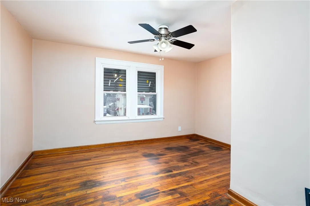 Empty room featuring wood-type flooring, ceiling fan, and baseboards