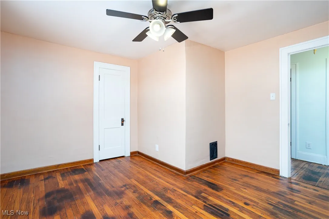 Empty room featuring baseboards, visible vents, a ceiling fan, and wood-type flooring