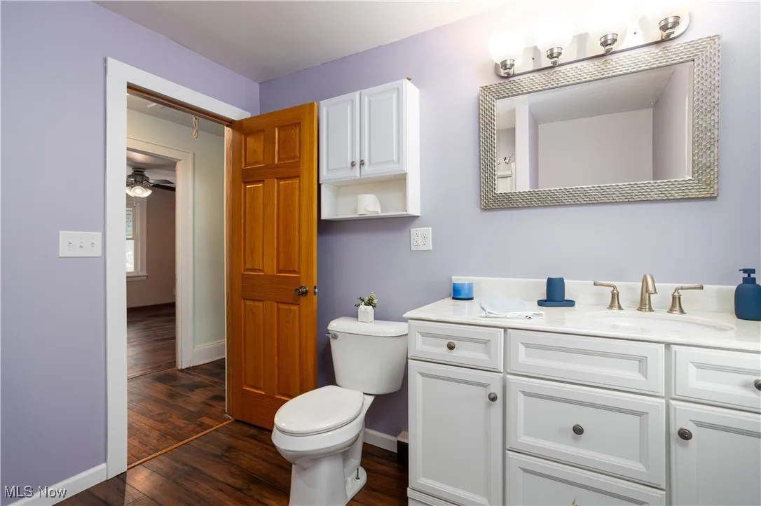 Bathroom featuring baseboards, wood finished floors, toilet, and vanity
