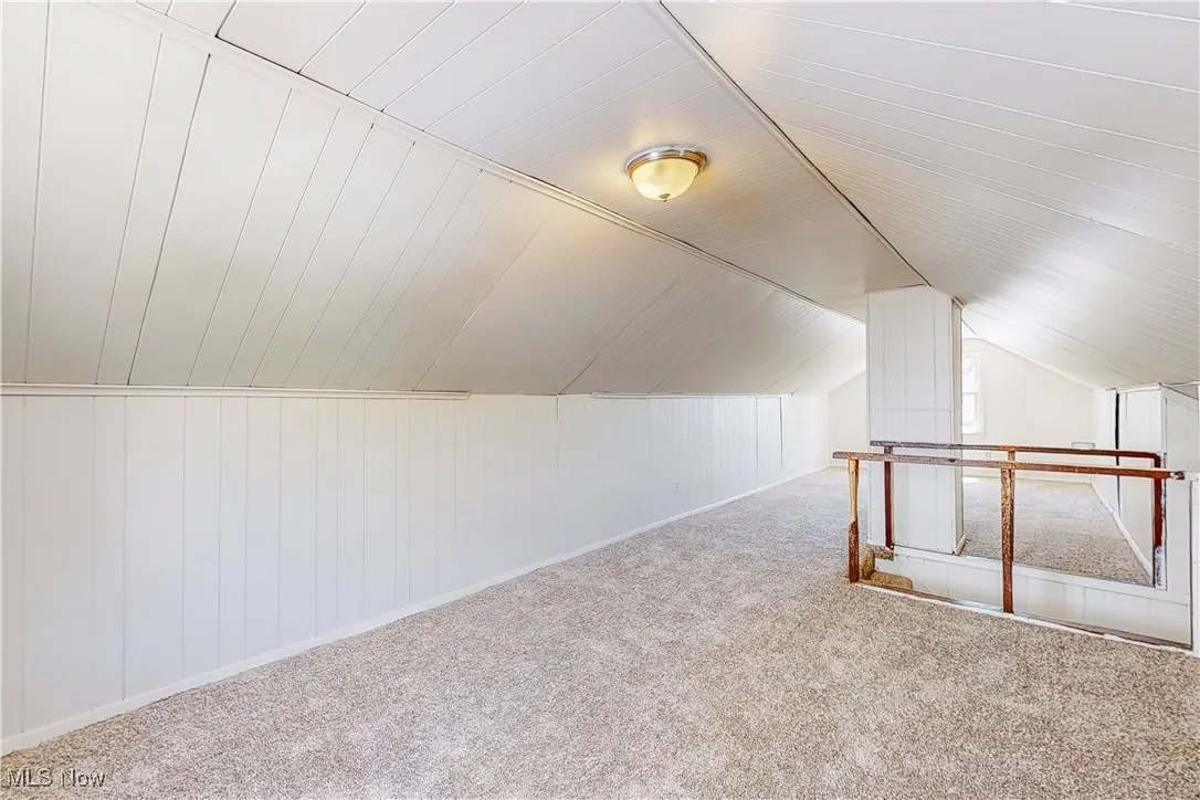 Additional living space with lofted ceiling and carpet