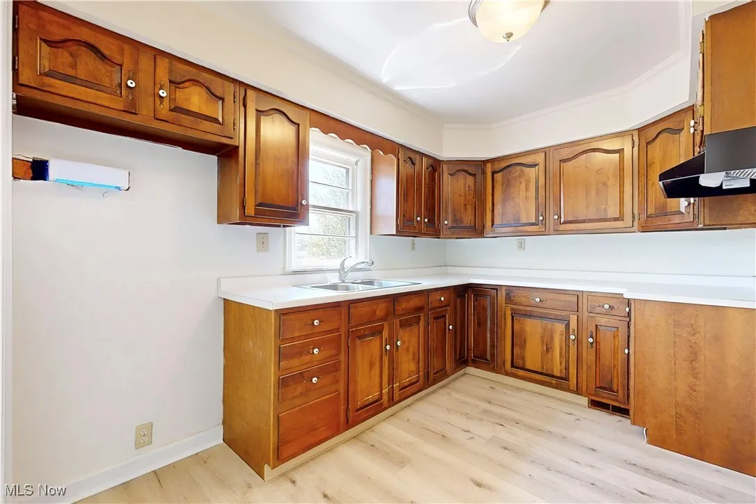 Kitchen with light wood-style flooring, brown cabinetry, and a sink