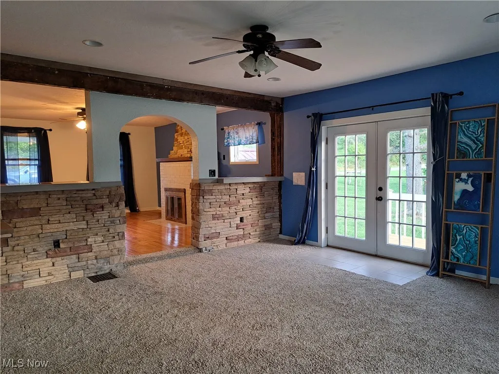 Living room with ceiling fan, light carpet, and french doors