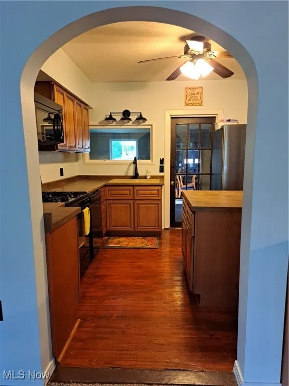 Kitchen featuring dishwashing machine, ceiling fan, dark hardwood / wood-style flooring, range, and refrigerator