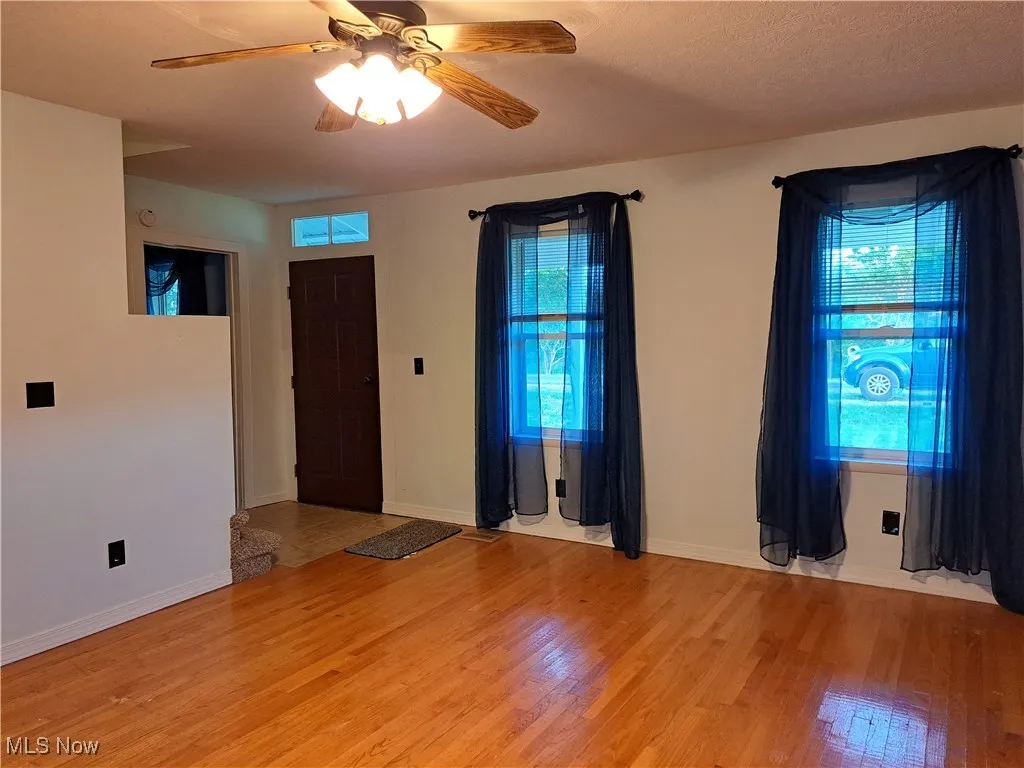 Empty room with ceiling fan and light wood-type flooring