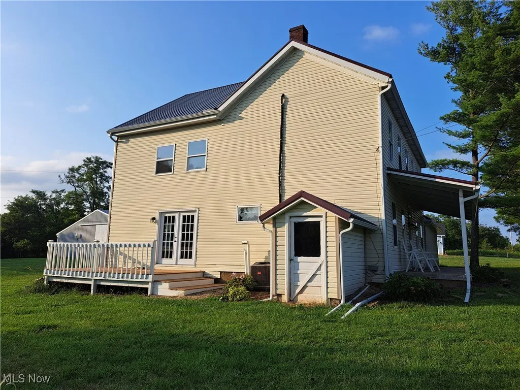 Side of house featuring a wooden deck, french doors, and a yard
