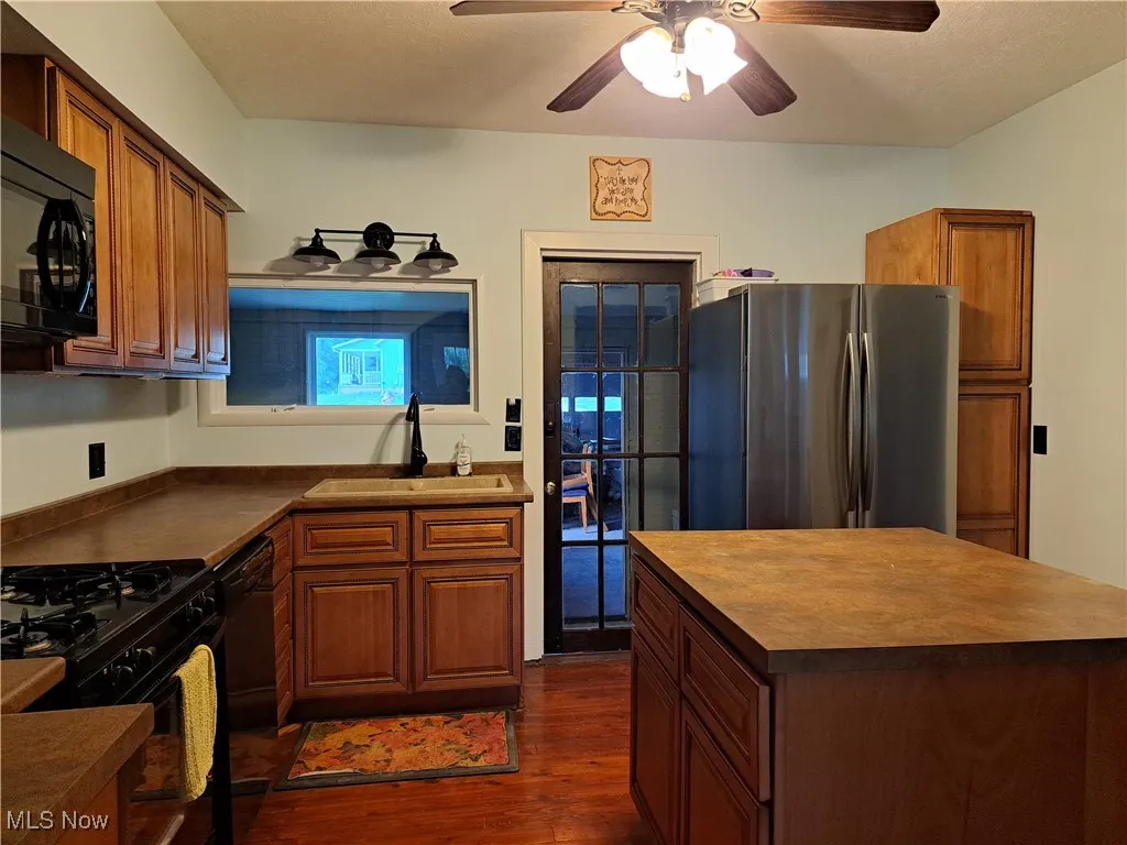 Kitchen with black appliance, dark hardwood / wood-style flooring, sink, and ceiling fan