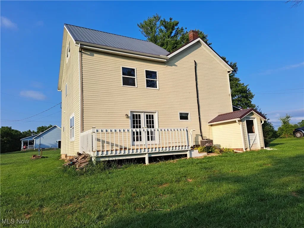 Side view of house featuring french doors, a deck, and a lawn