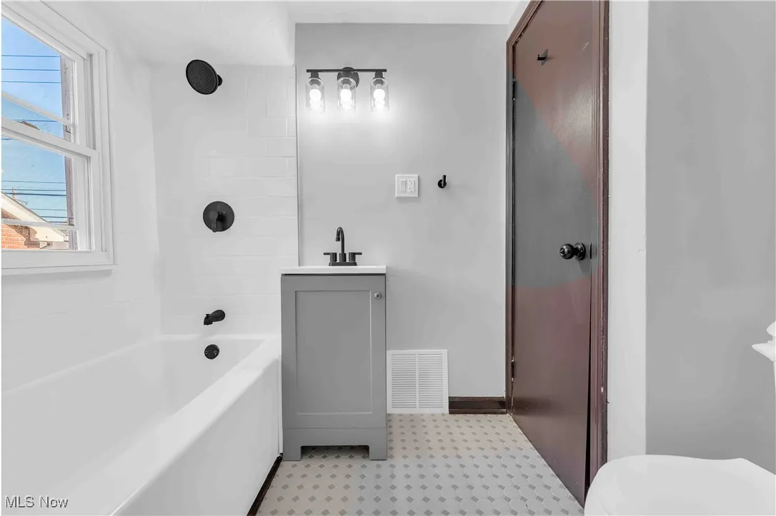 Full bath with tile patterned floors, toilet, shower / bathing tub combination, a sink, and visible vents