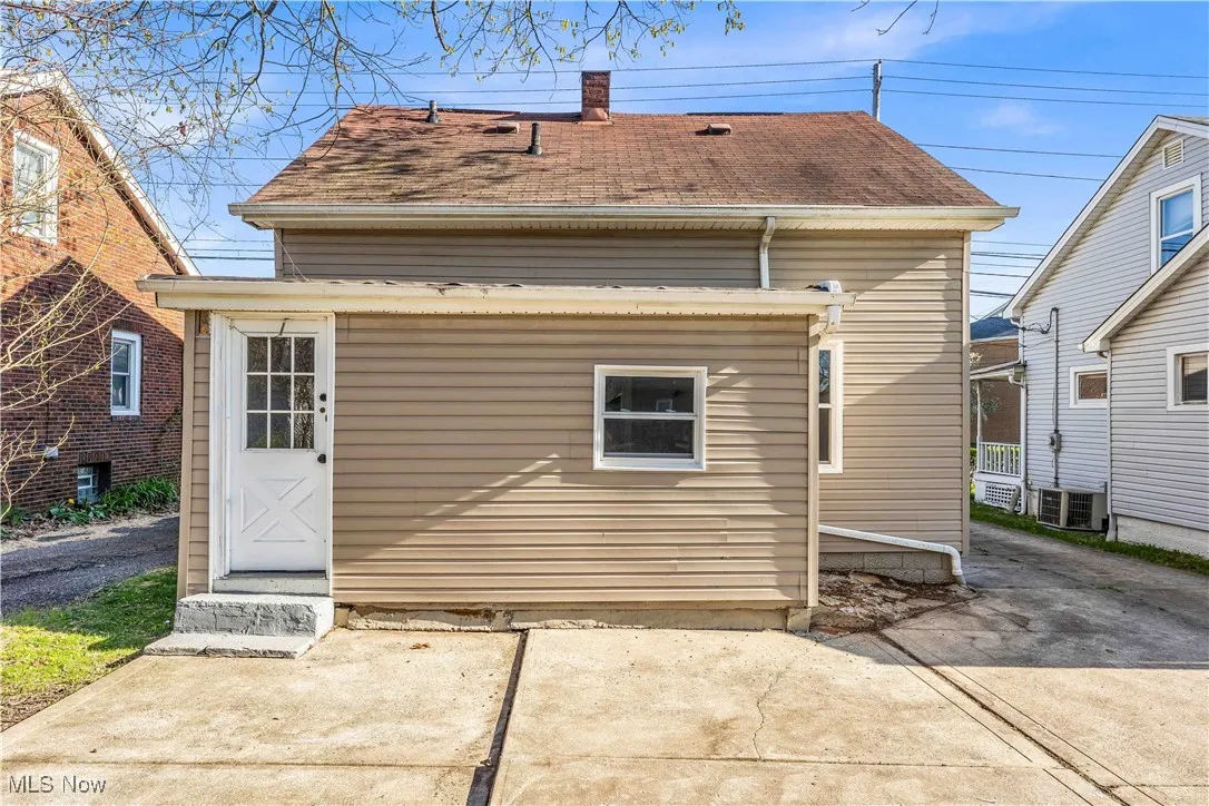 Rear view of house featuring central air condition unit and a shingled roof
