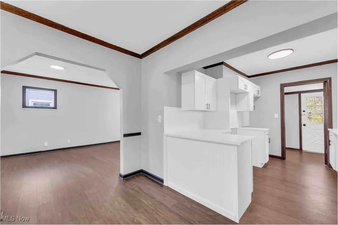 Kitchen with white cabinetry, crown molding, and dark wood-style floors