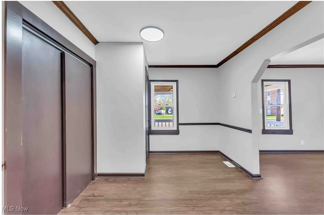 Corridor featuring wood finished floors, ornamental molding, and baseboards
