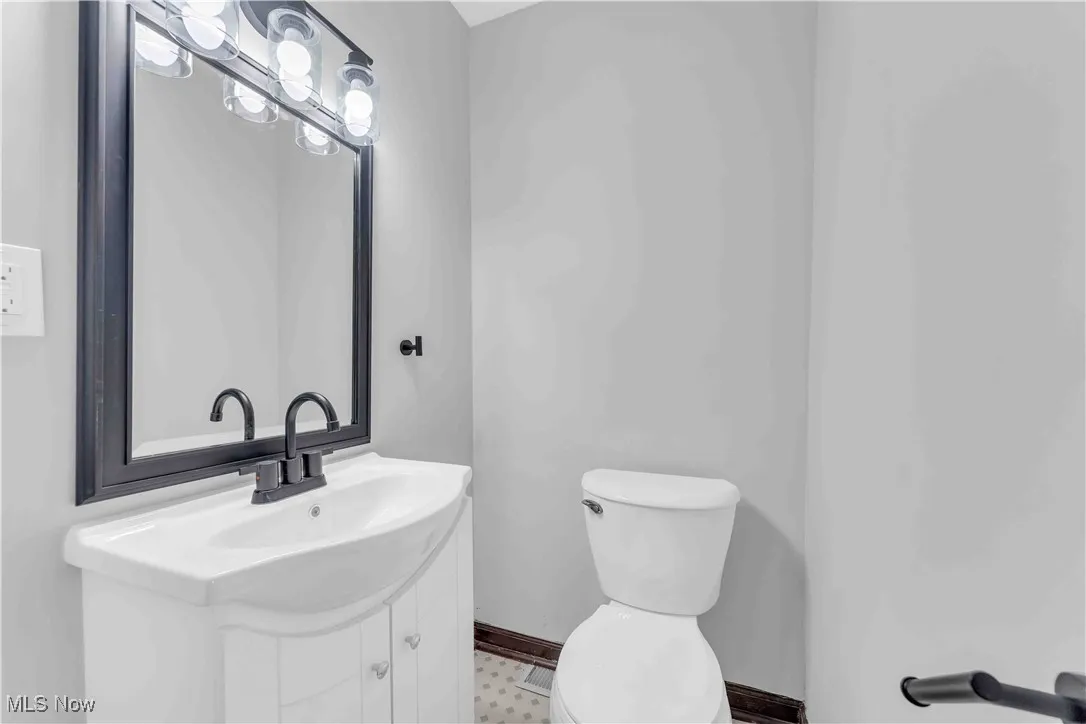 Half bath with baseboards, toilet, and vanity