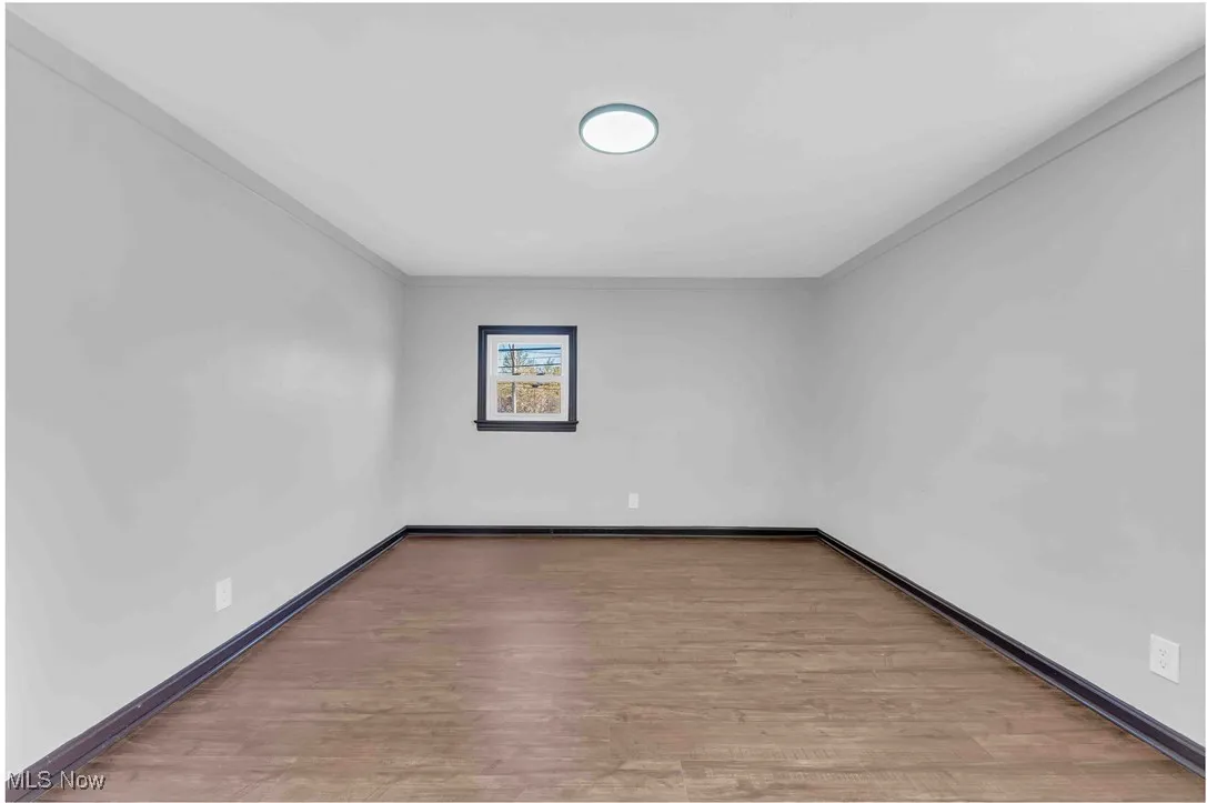Unfurnished room featuring ornamental molding, wood finished floors, and baseboards