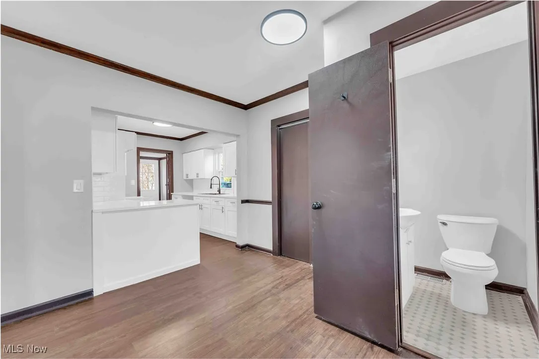 Bathroom with crown molding, baseboards, toilet, wood finished floors, and vanity