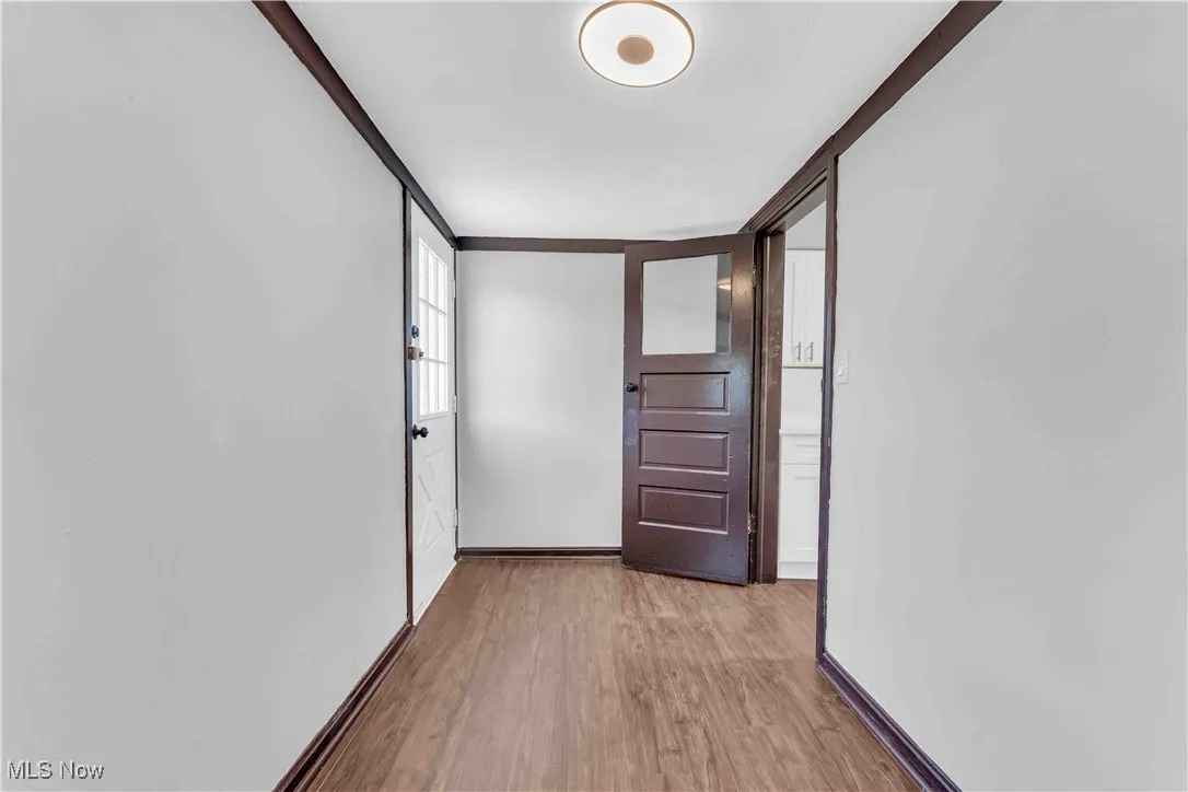 Corridor with light wood-style flooring and baseboards