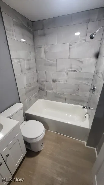 Bathroom featuring wood finished floors, toilet, vanity, and washtub / shower combination