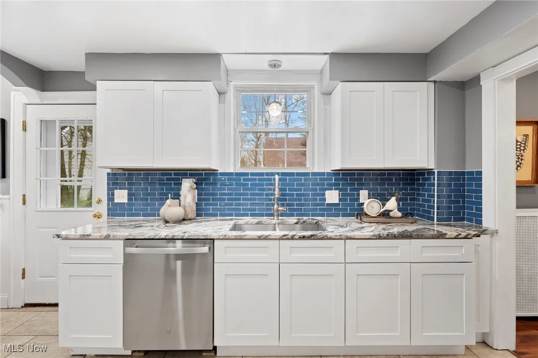 Kitchen with a wealth of natural light, sink, stainless steel dishwasher, and white cabinets