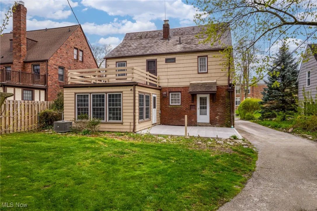 Rear view of house with central air condition unit, a patio area, and a lawn
