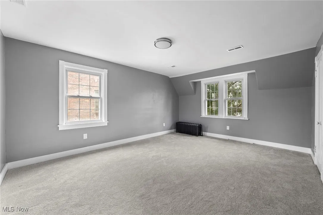 Bonus room featuring vaulted ceiling, carpet, and radiator heating unit