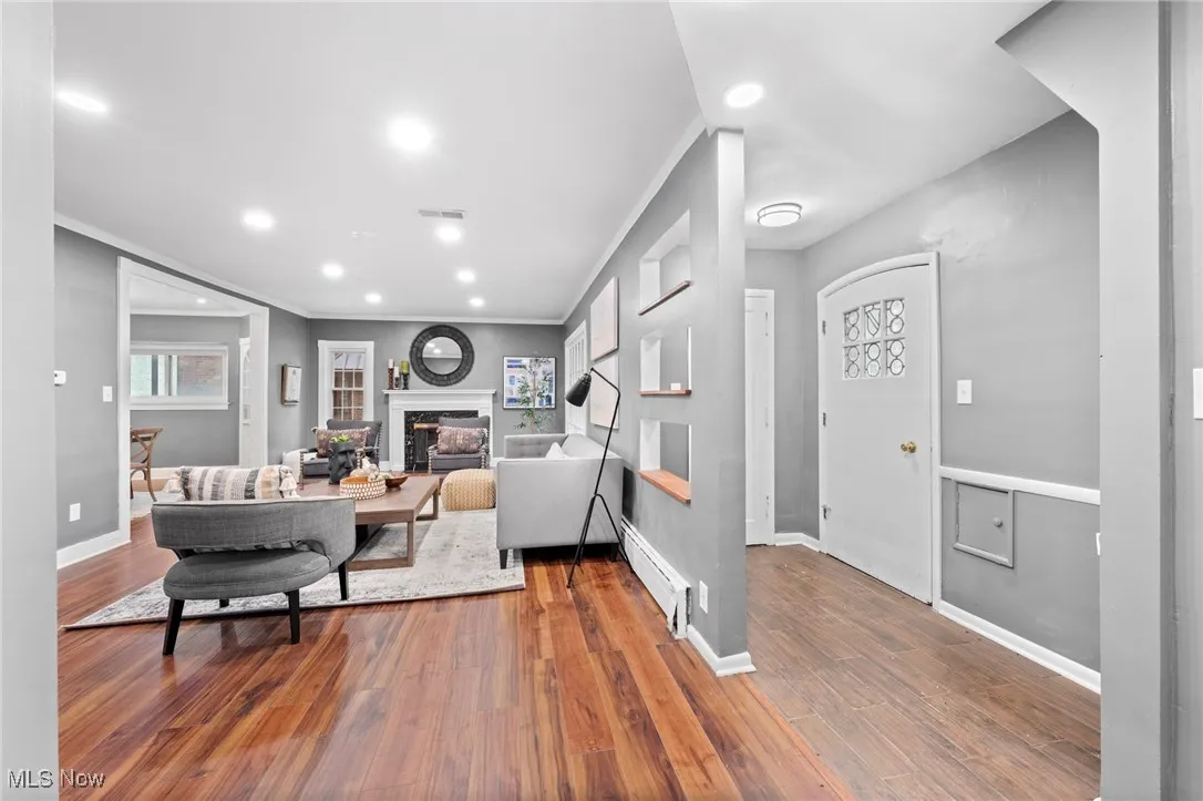 Living room featuring crown molding, a baseboard heating unit, and hardwood / wood-style floors
