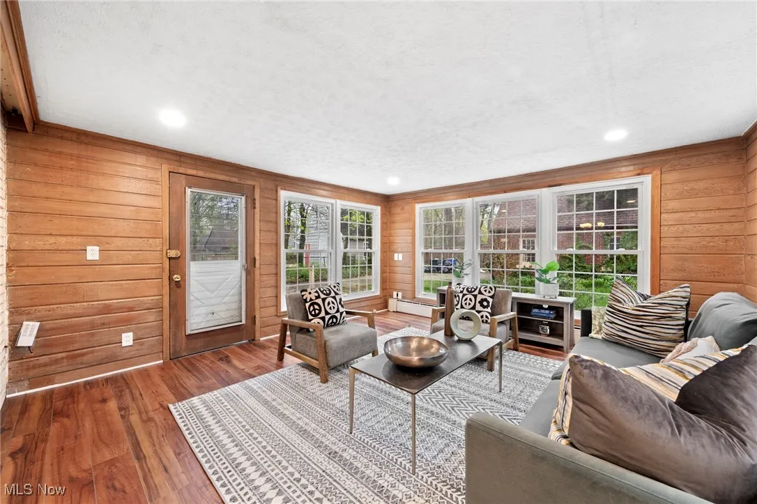 Living room with wood walls, a textured ceiling, and wood-type flooring
