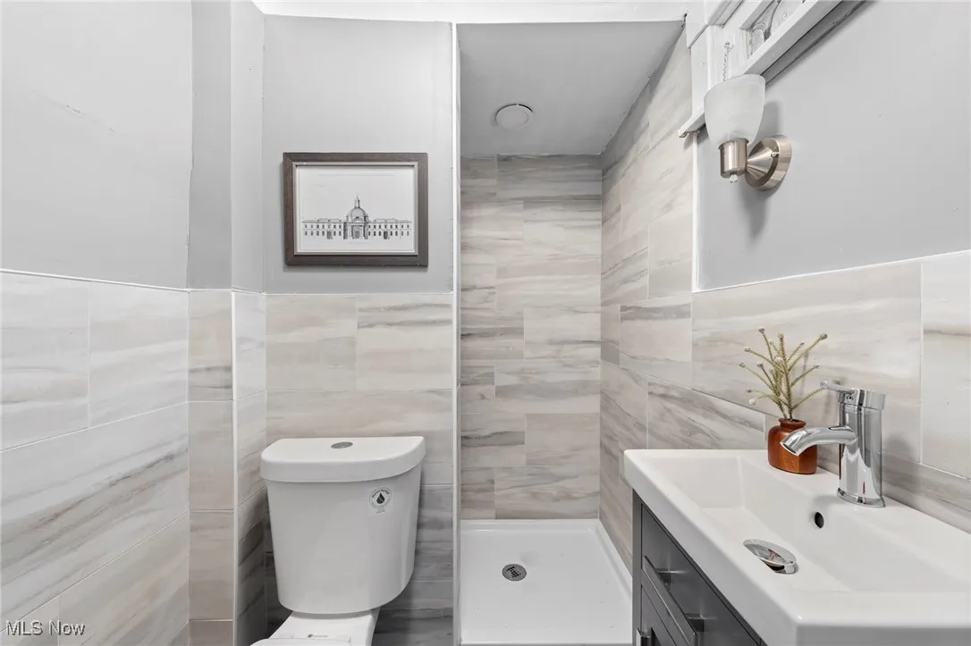 Bathroom with vanity, toilet, tile walls, and walk in shower