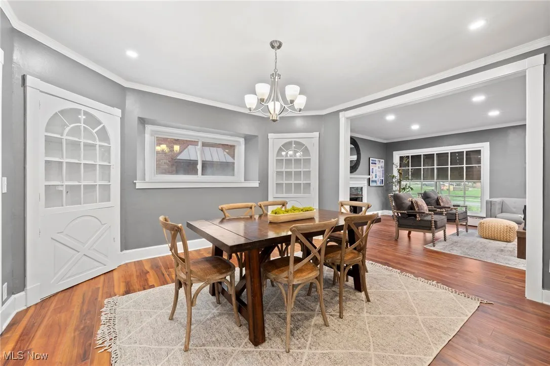 Dining space with ornamental molding, an inviting chandelier, and hardwood / wood-style floors