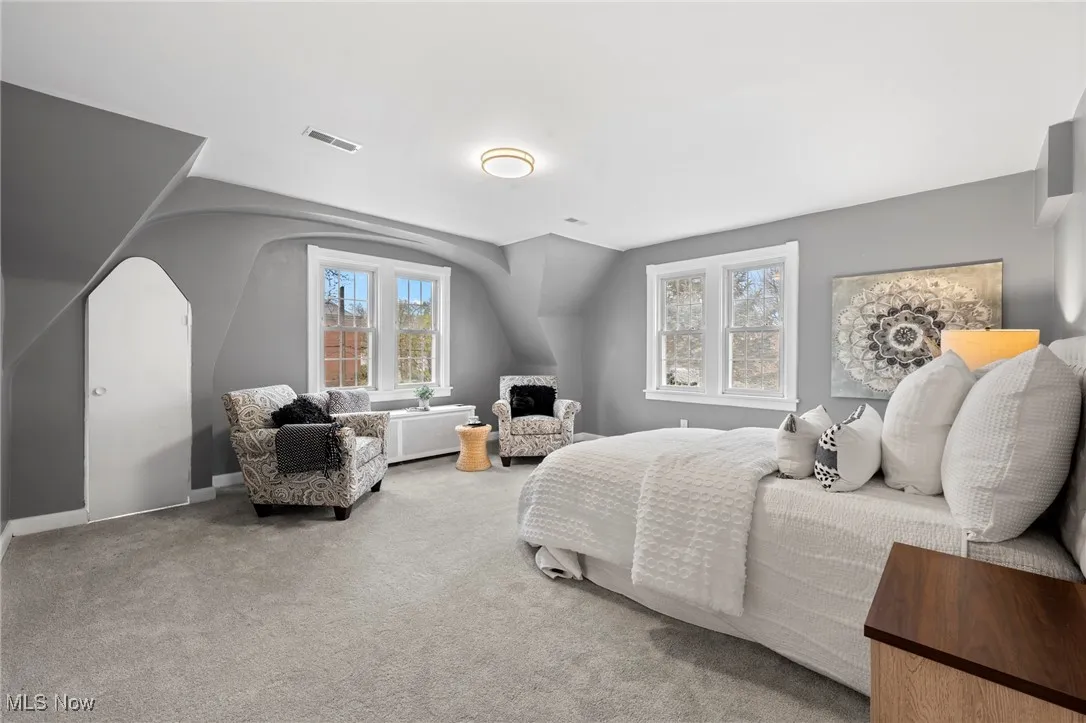 Bedroom featuring lofted ceiling, carpet, and multiple windows